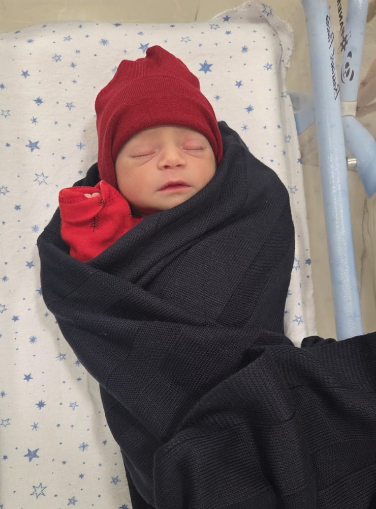 Adam de gorro vermelho, enrolado numa manta preta